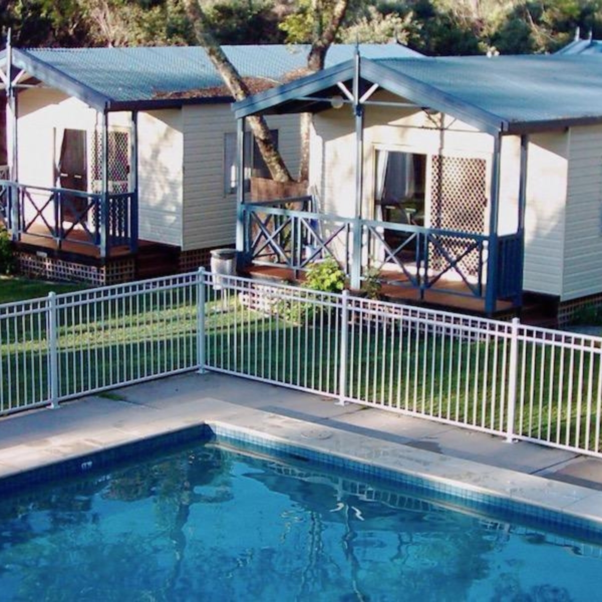 Beach park tourist caravan park aerial shot of pool and cabins.