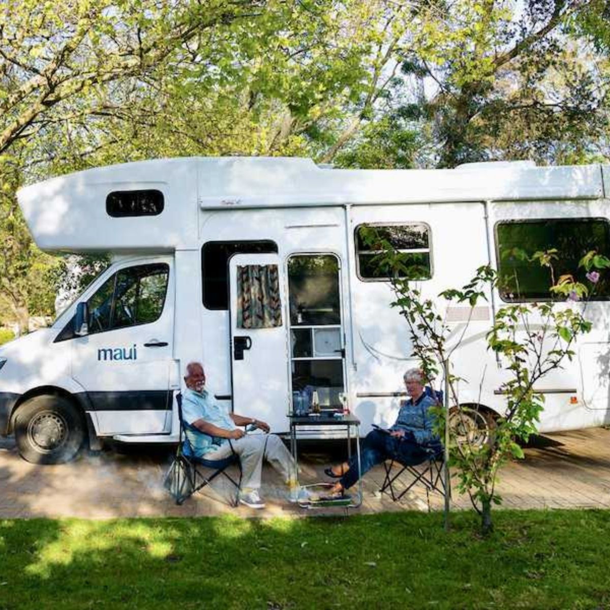 beach park tourist caravan park campervan with two older people sitting outside on camp chairs